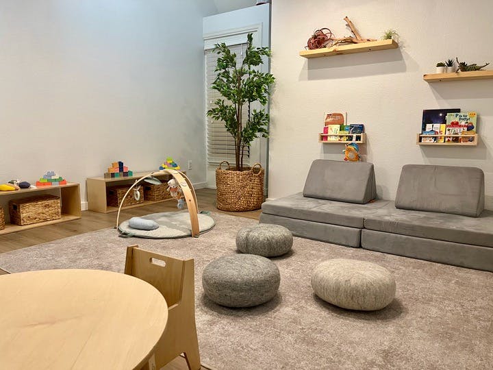 Children's play area with floor cushions, low shelves, and a baby play gym