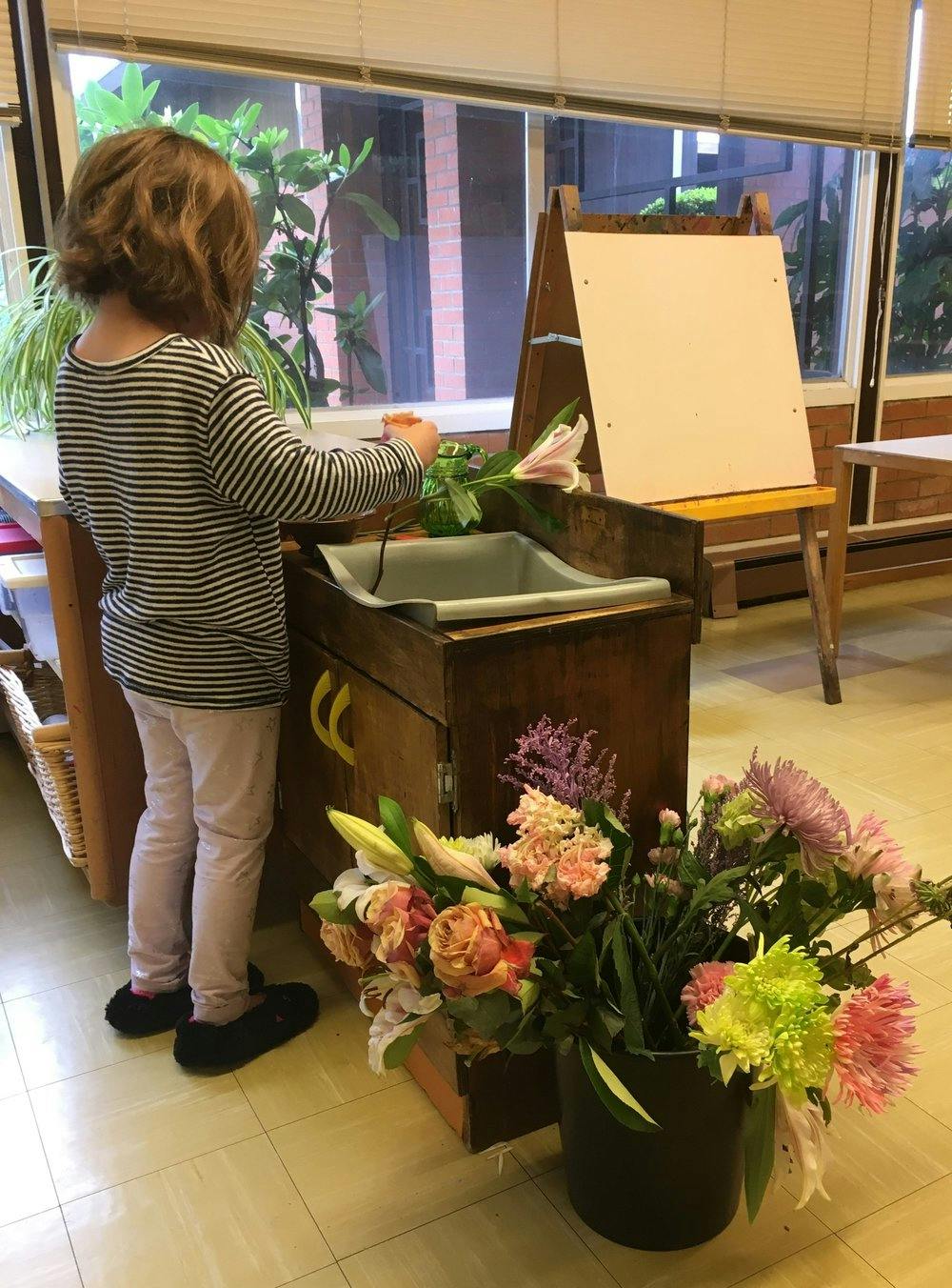 Child arranging flowers in a classroom
