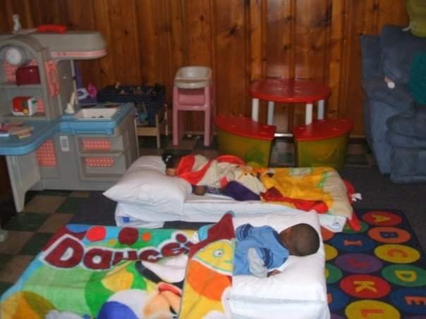Two babies sleeping on beds in a room with toys