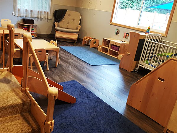 Playroom with small wooden tables, chairs, and play structures