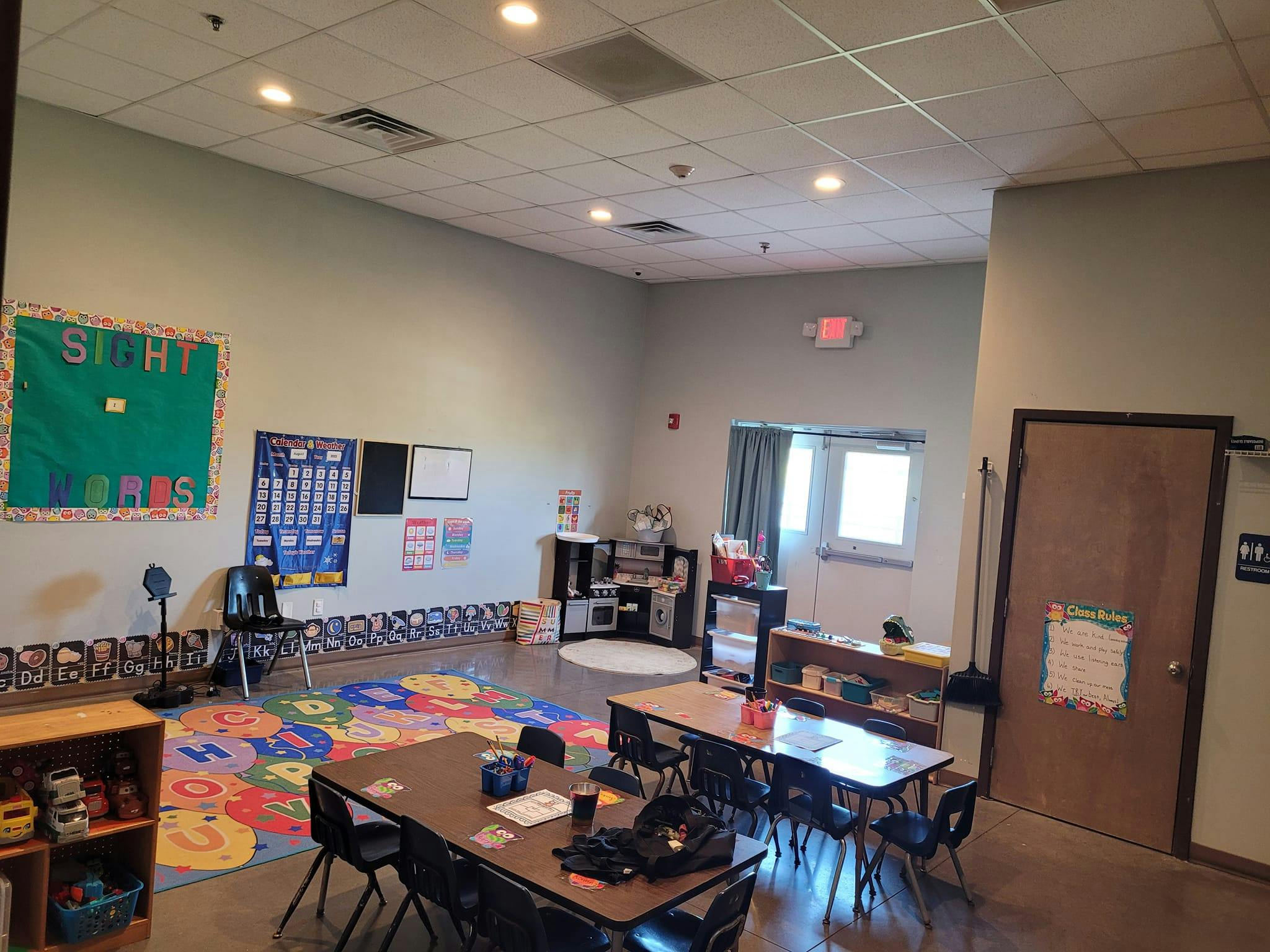 Classroom with tables, chairs, and colorful rug