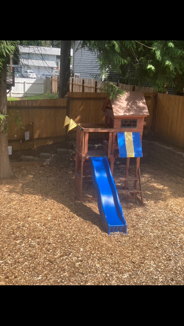 Wooden play structure with a blue slide in a backyard