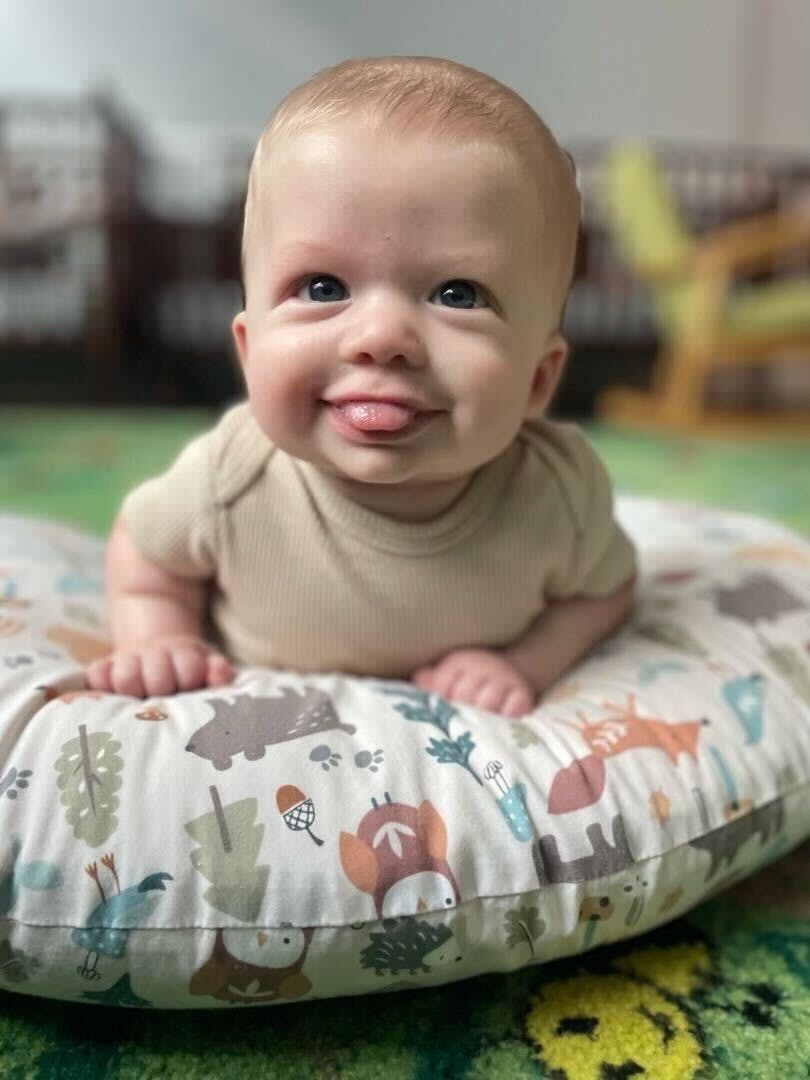 Child on a patterned pillow sticking out tongue