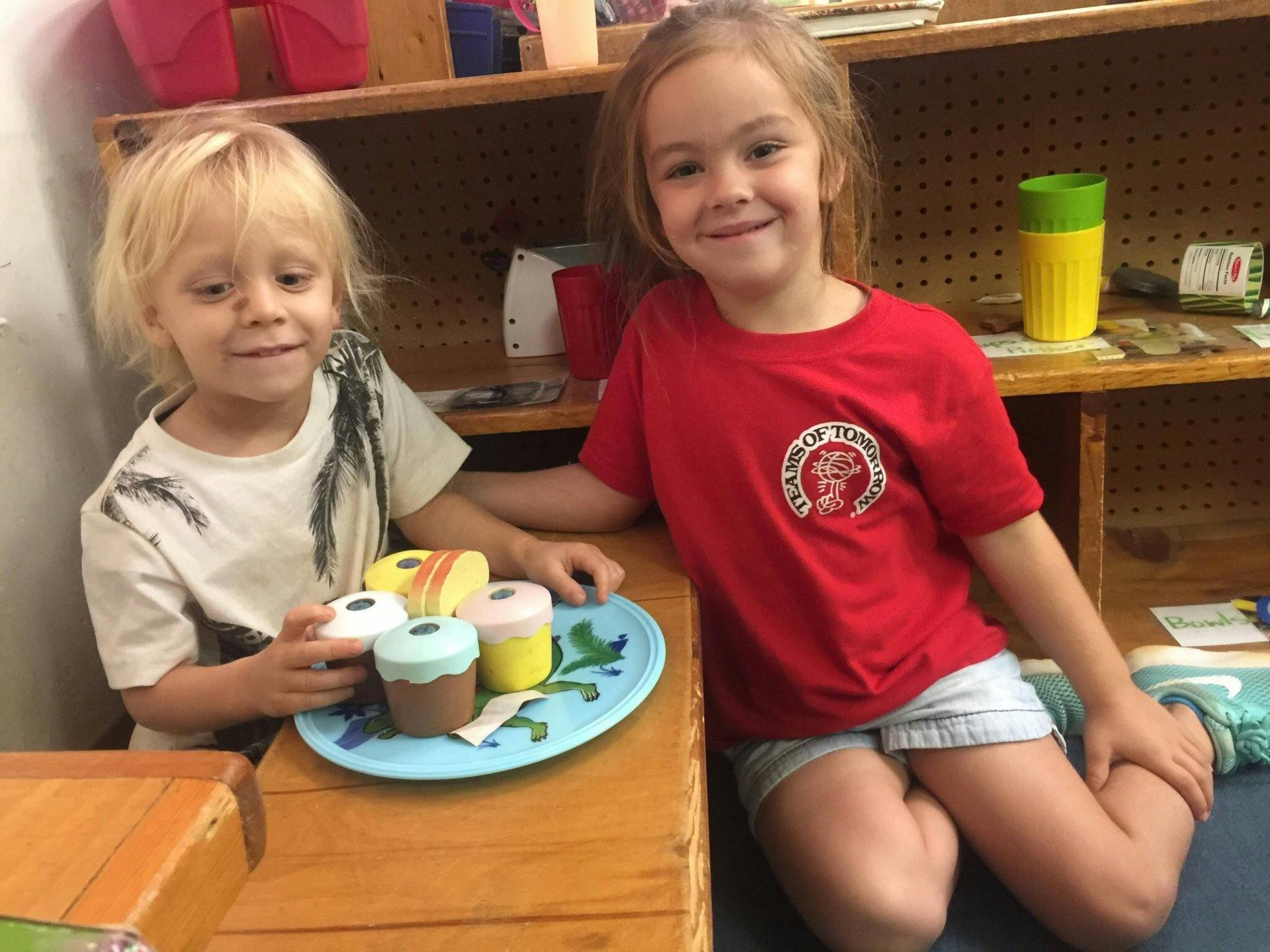 Two children playing with toy food on a blue plate