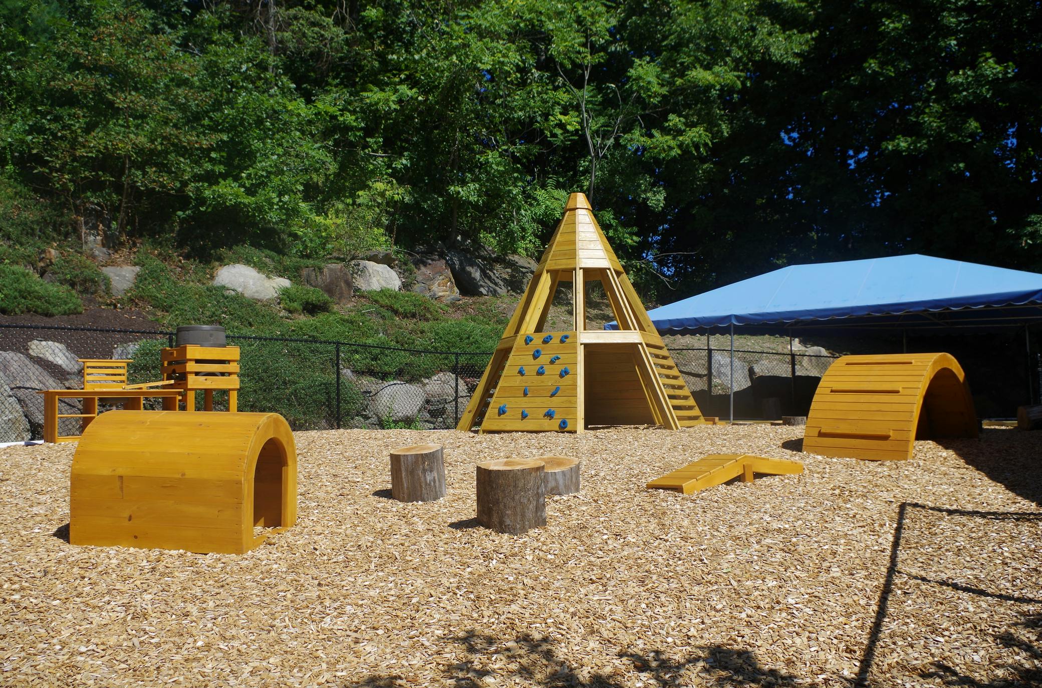 Outdoor playground with wooden climbing structures and wood chip ground