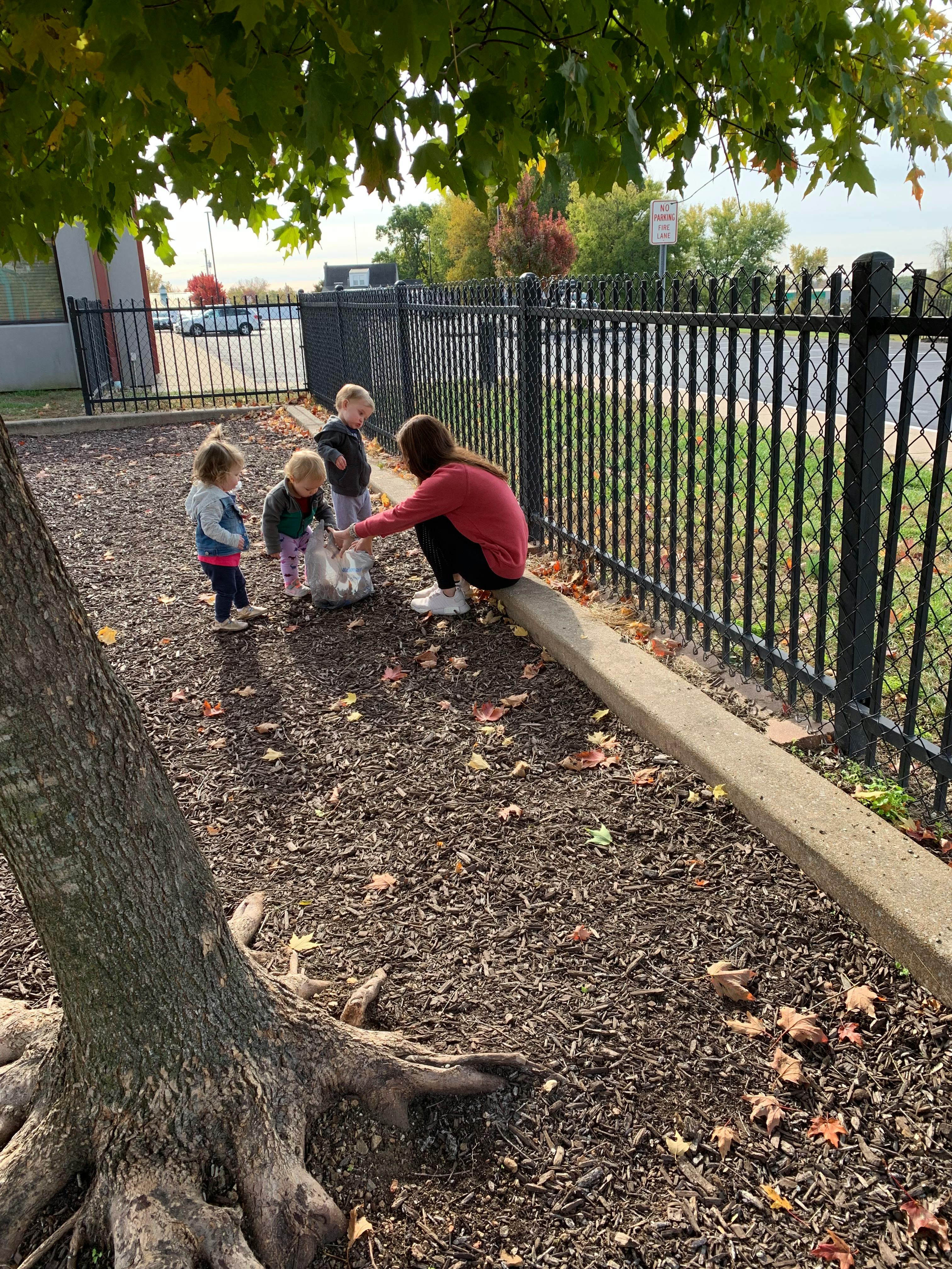 Adult and three children outdoors near a fence