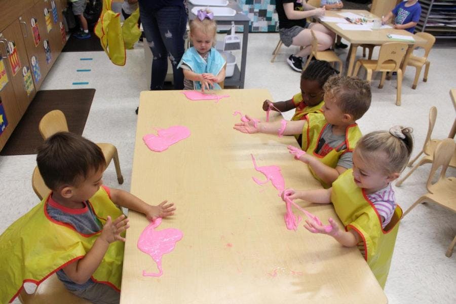 Children playing with pink paint at a table