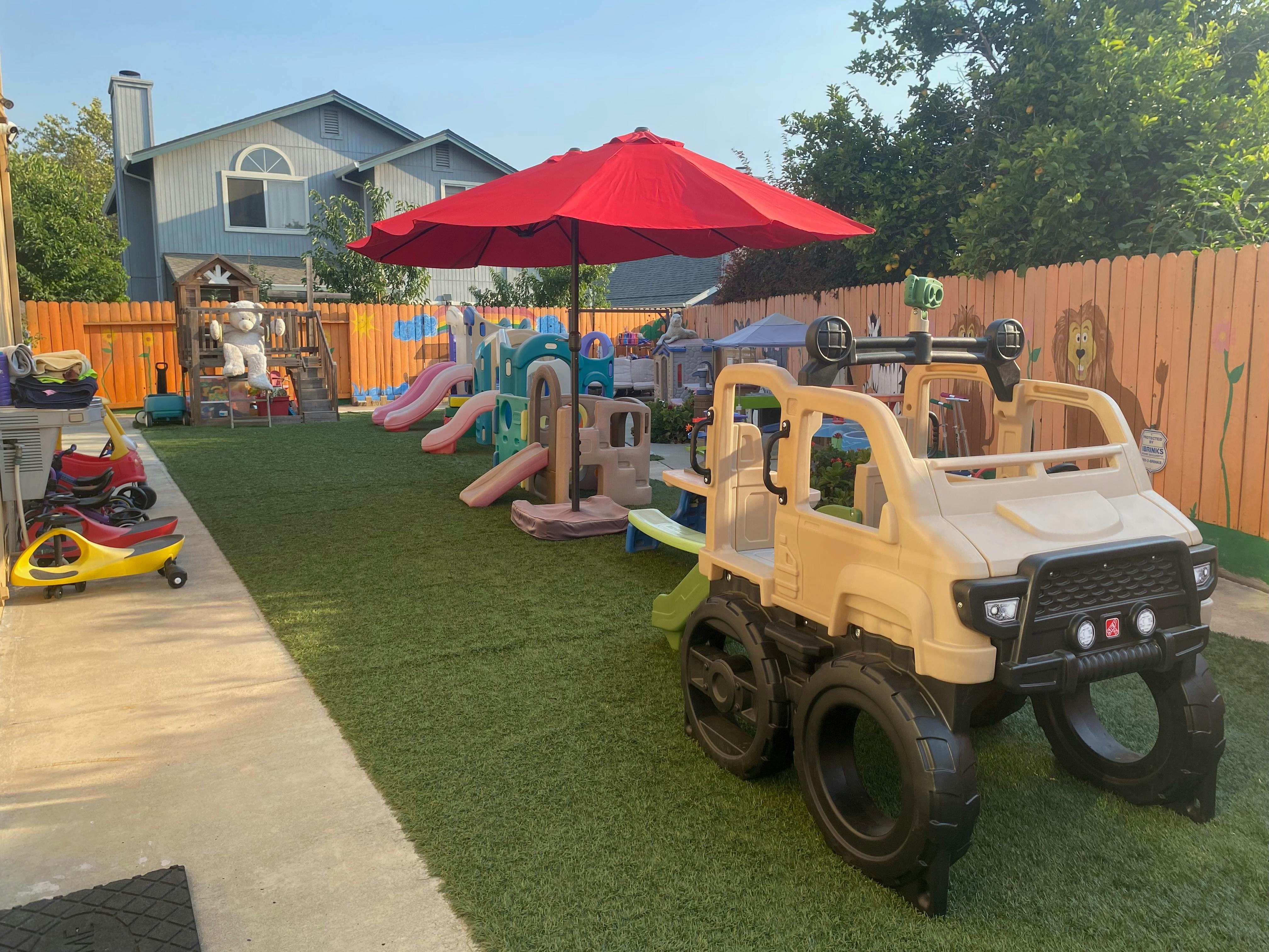 Playground with slides, play structures, and ride-on toys on artificial turf
