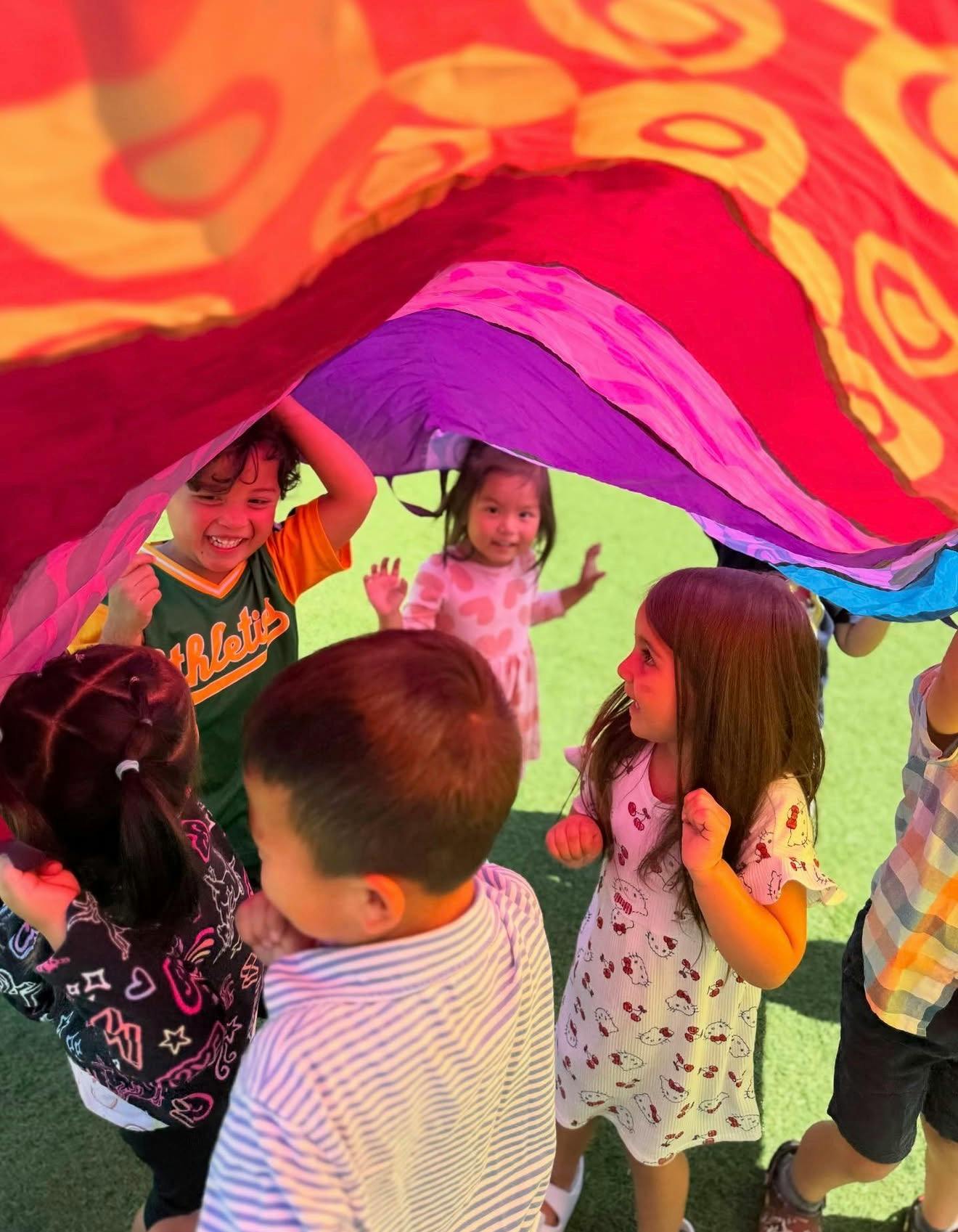 Children playing with a colorful parachute