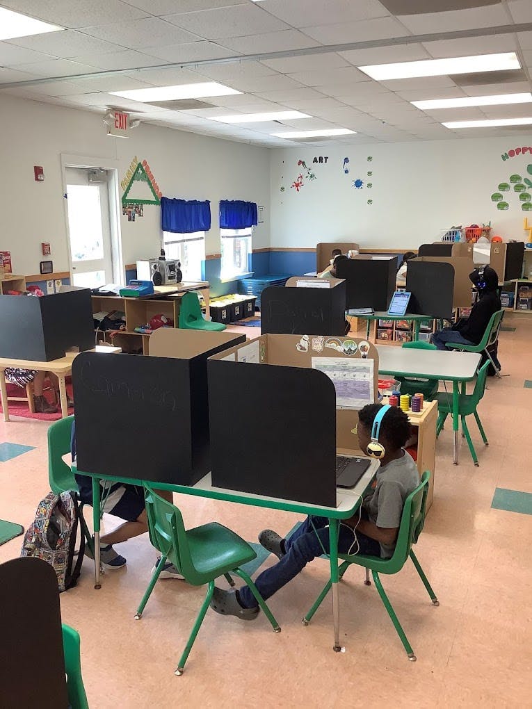 Children in a classroom working at desks with privacy shields