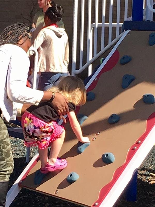 Person helping a child climb a rock wall