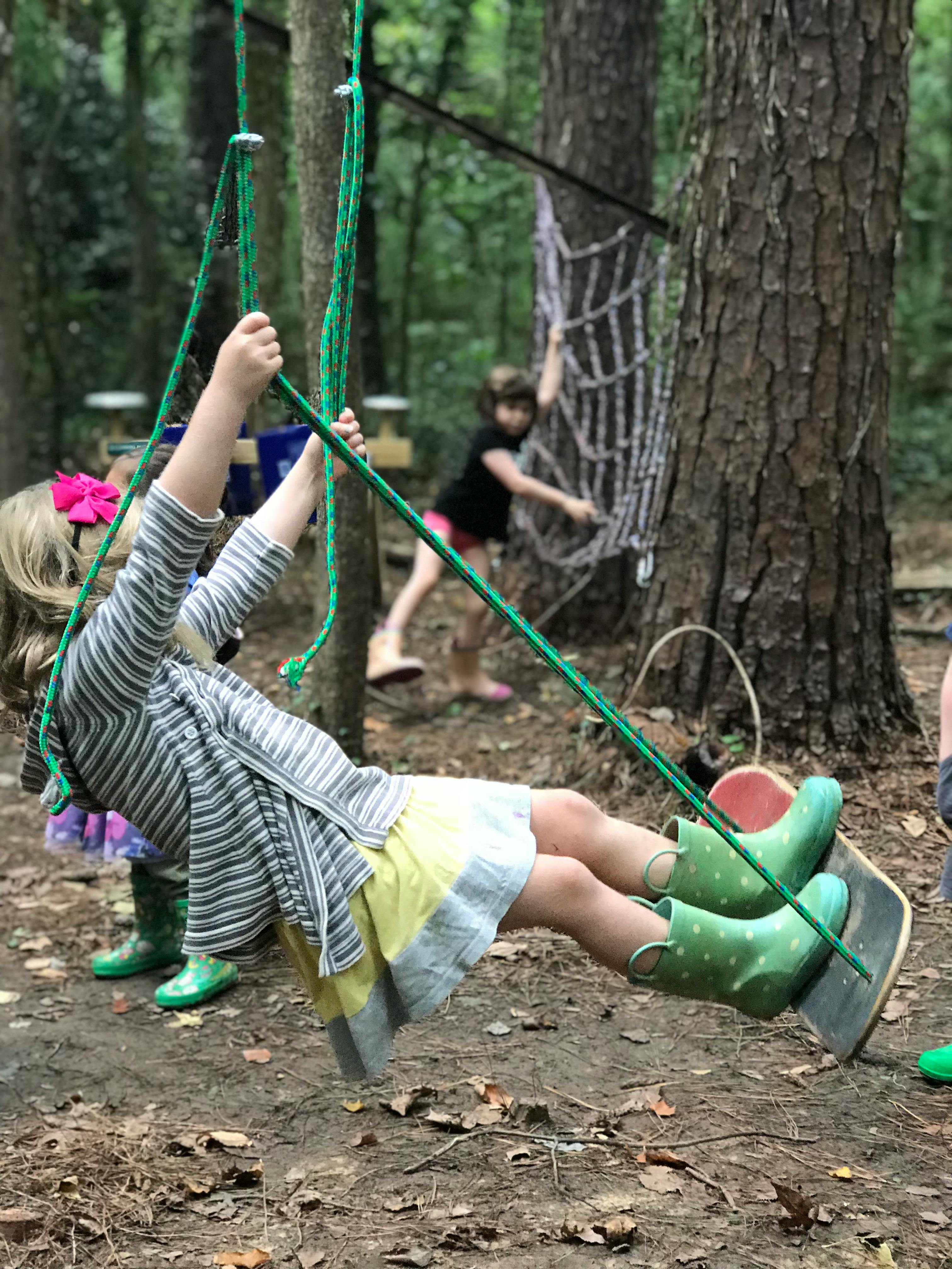 Child swinging on a rope swing in a wooded area