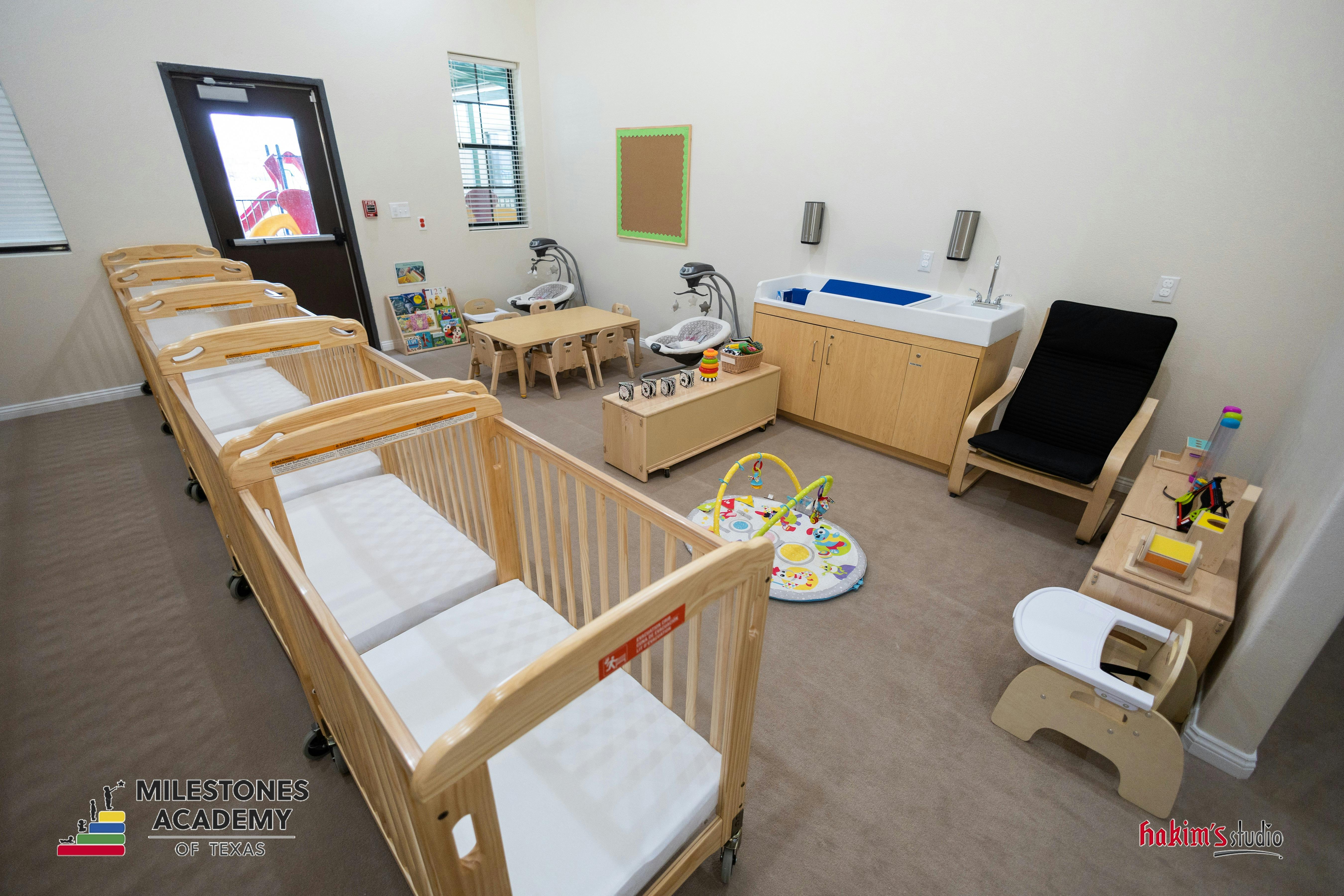 Classroom for babies with cribs, changing station, small tables, and play mats