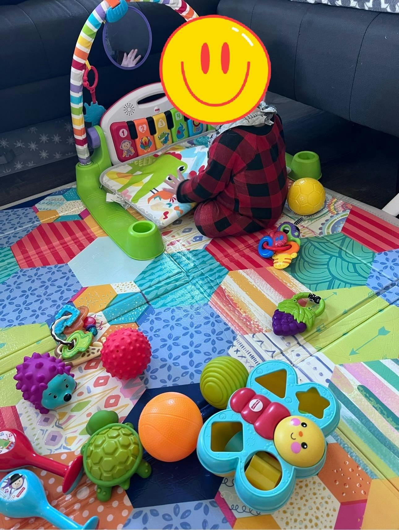 Child playing with a musical activity center and toys on a colorful mat