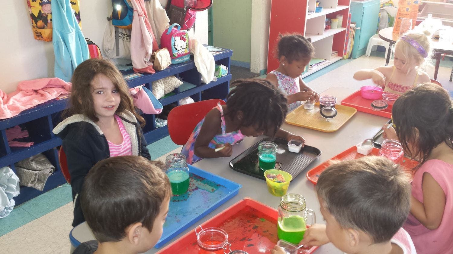Children at a table with colorful liquids in a classroom