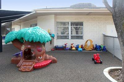 Playground with a tree-shaped playhouse and various ride-on toys