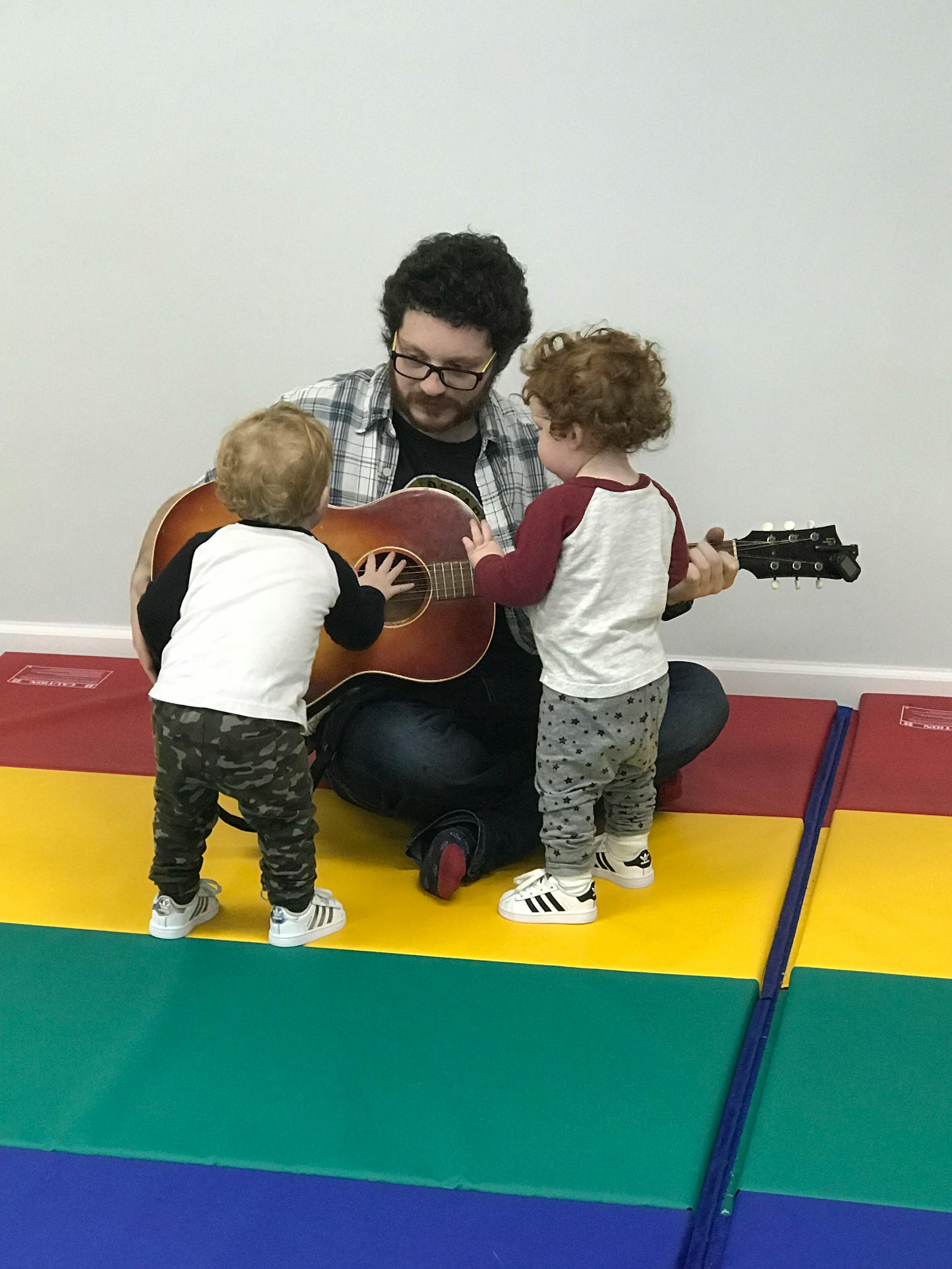 Person playing guitar for two children