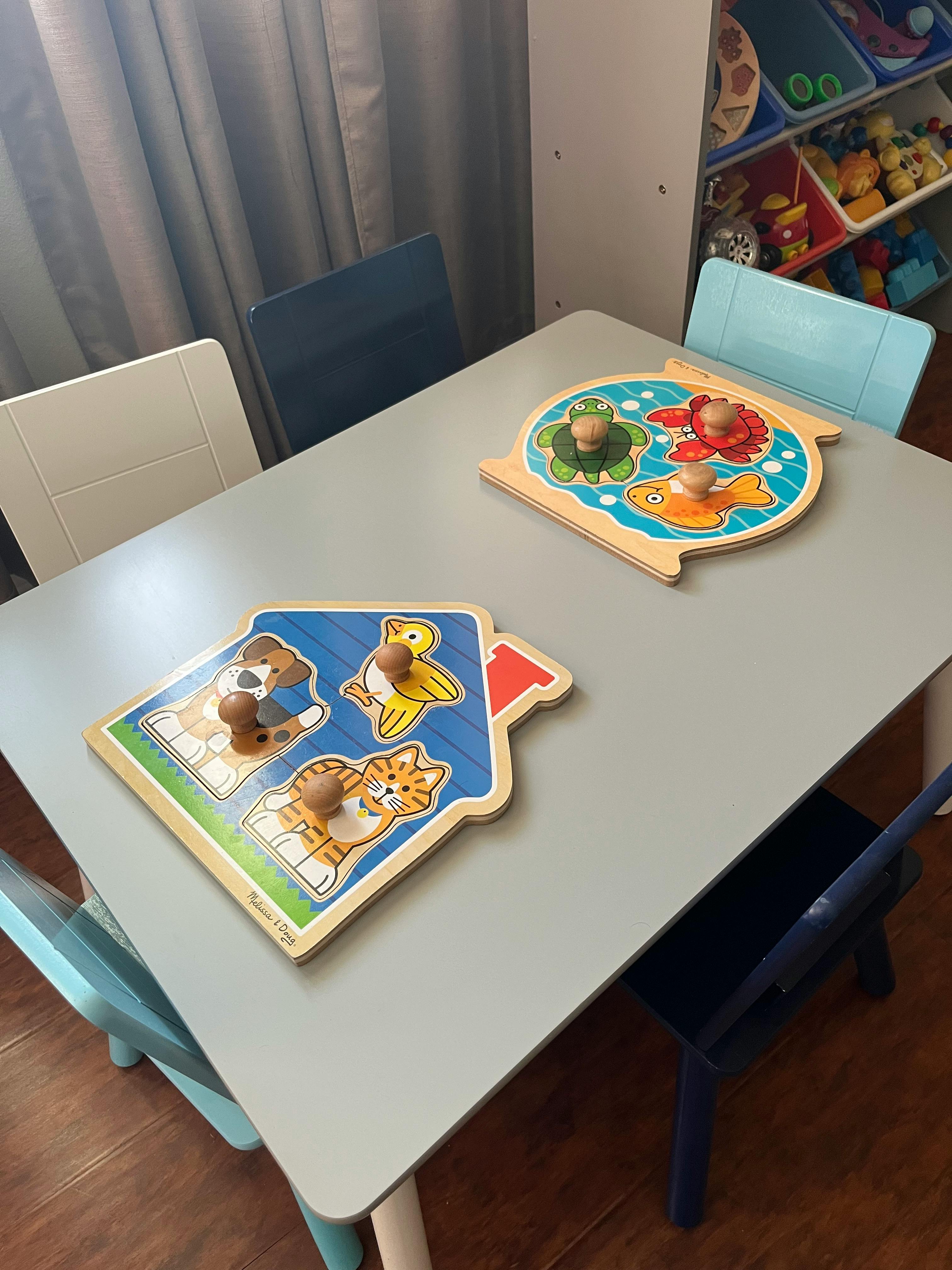 Two wooden puzzles on a table with chairs
