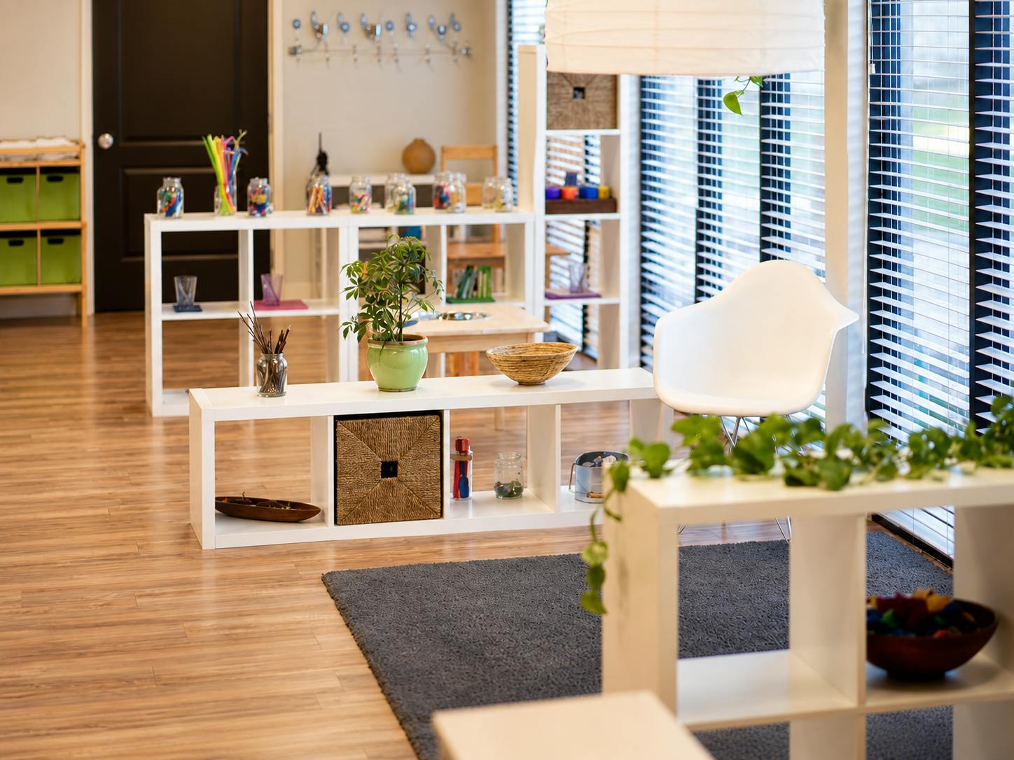Classroom interior with white shelving units containing toys and decorative plants