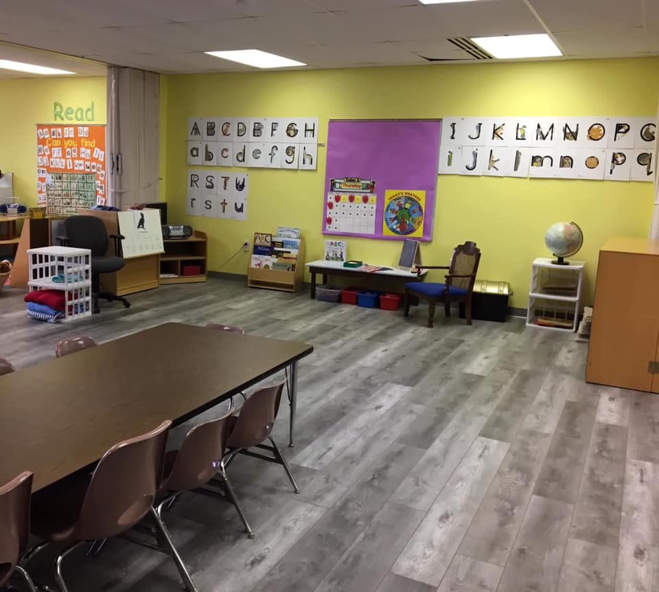 Empty classroom with tables, chairs, and alphabet charts on the wall
