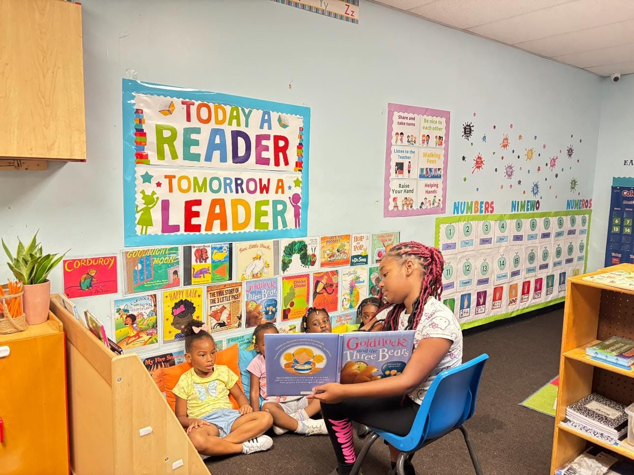 Person reading a book to children in a classroom
