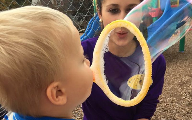 Child looking at a large bubble being blown by a person