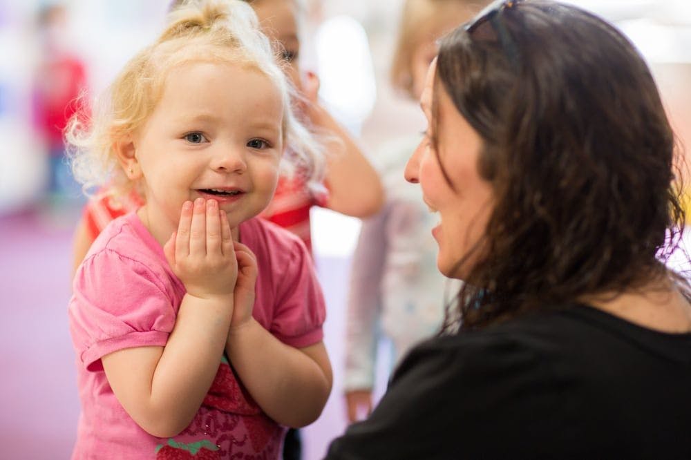 Child with hands clasped looking at a person