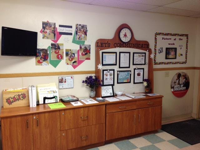 display board with information, photos of children, and a television on a wall
