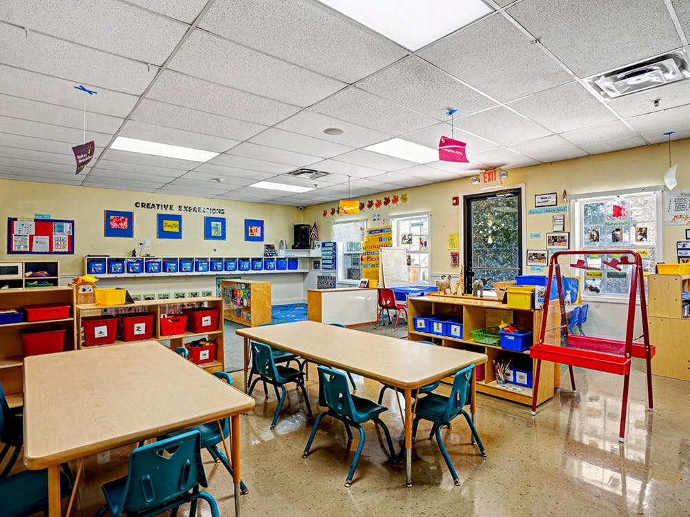 Classroom with tables, chairs, shelving units, and art displays on the walls