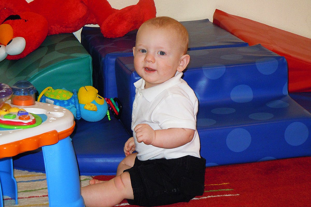 Child sitting on floor next to play table and soft play equipment