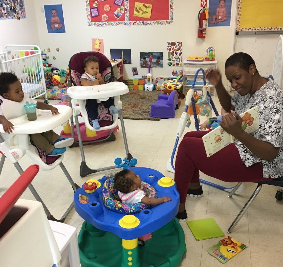 Person reading to three children in a playroom