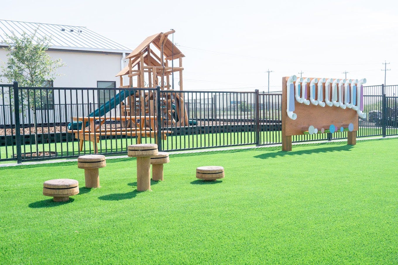 Playground equipment with stepping stools and a play wall on artificial turf