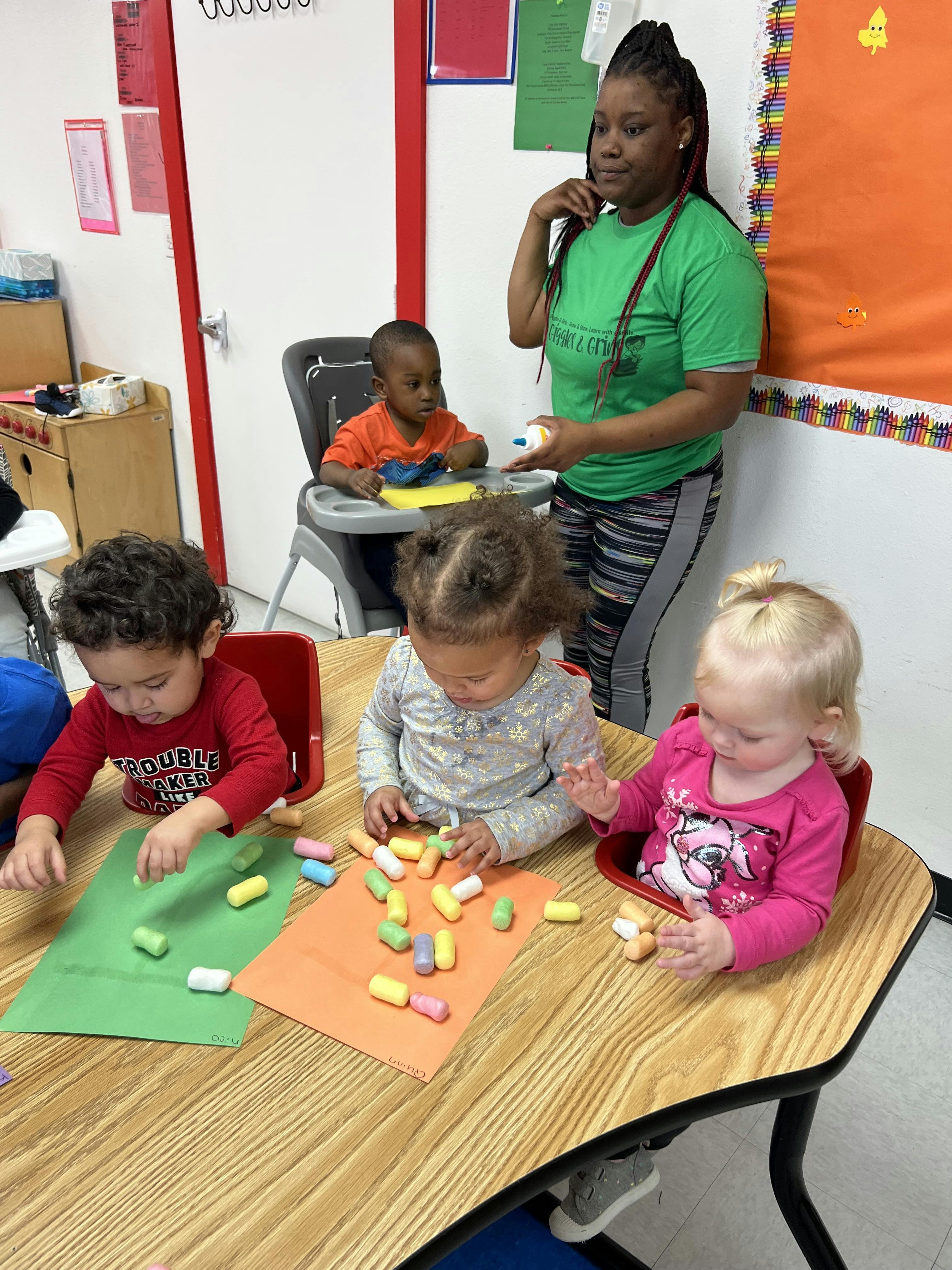 Adult supervising children playing with colorful blocks at a table