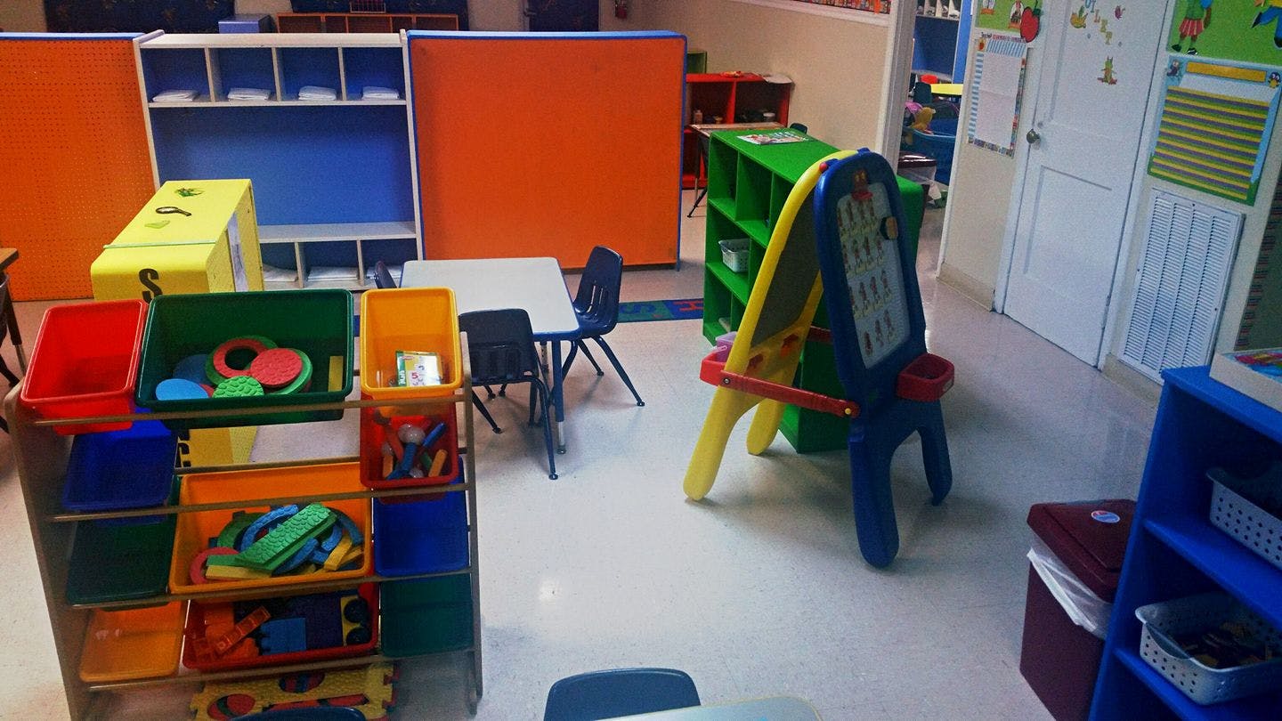 Classroom with colorful storage bins, tables, and an easel