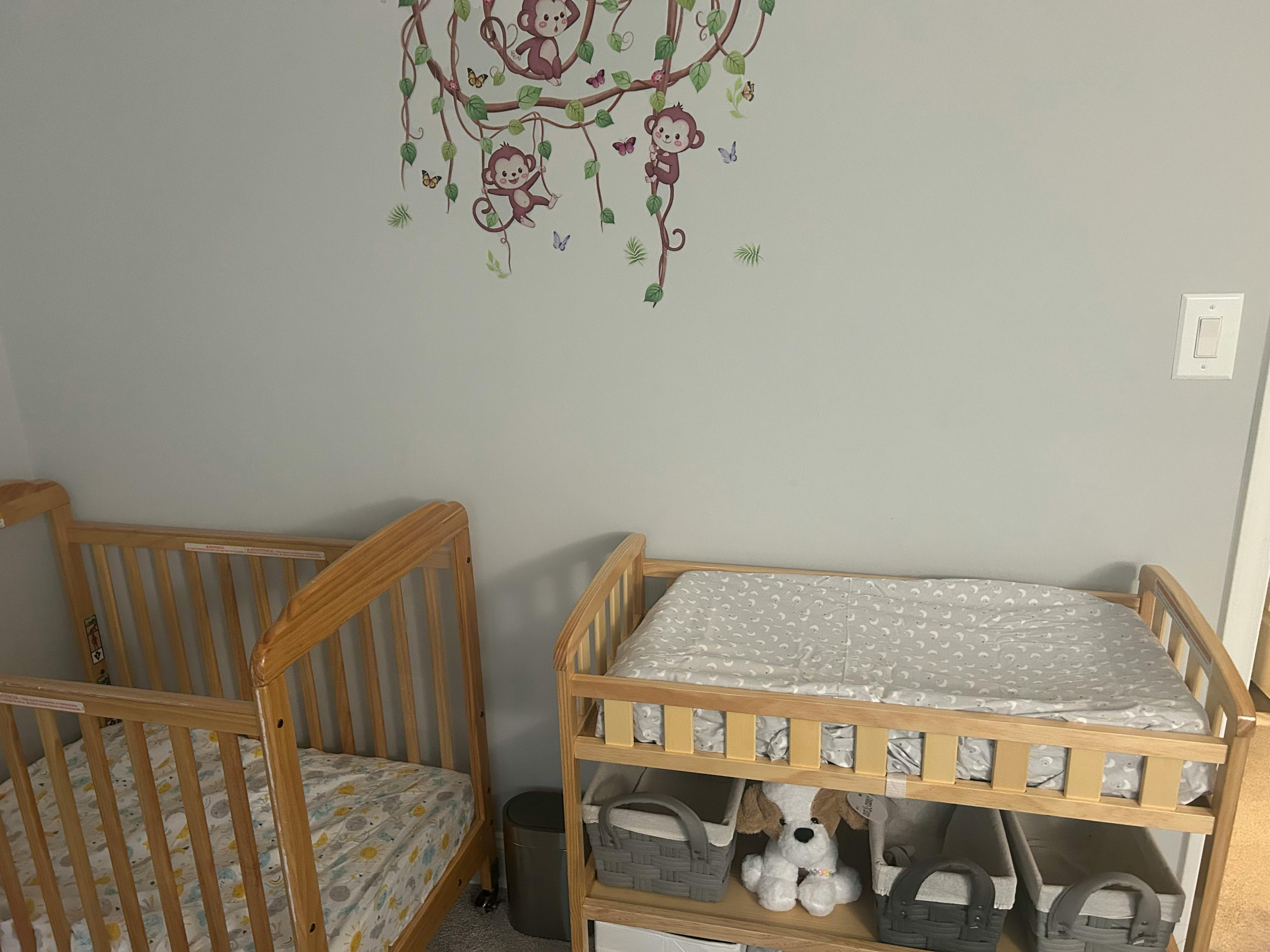 Crib and changing table in a nursery with monkey wall decals