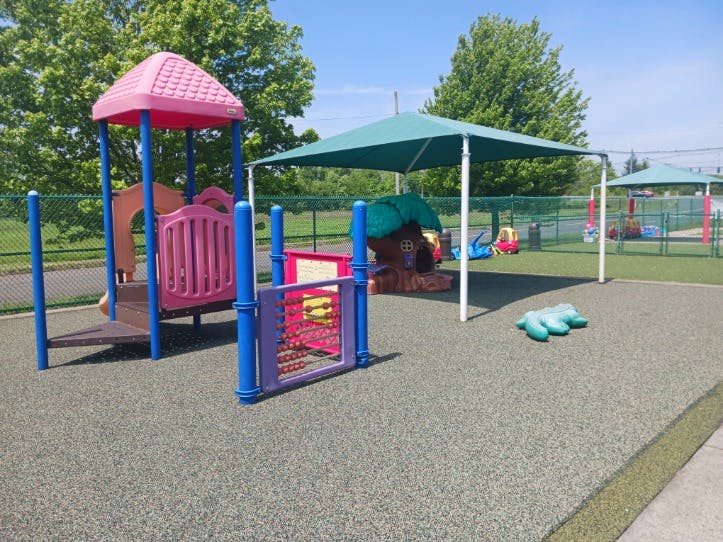 Empty children's playground with a pink play structure and a green canopy