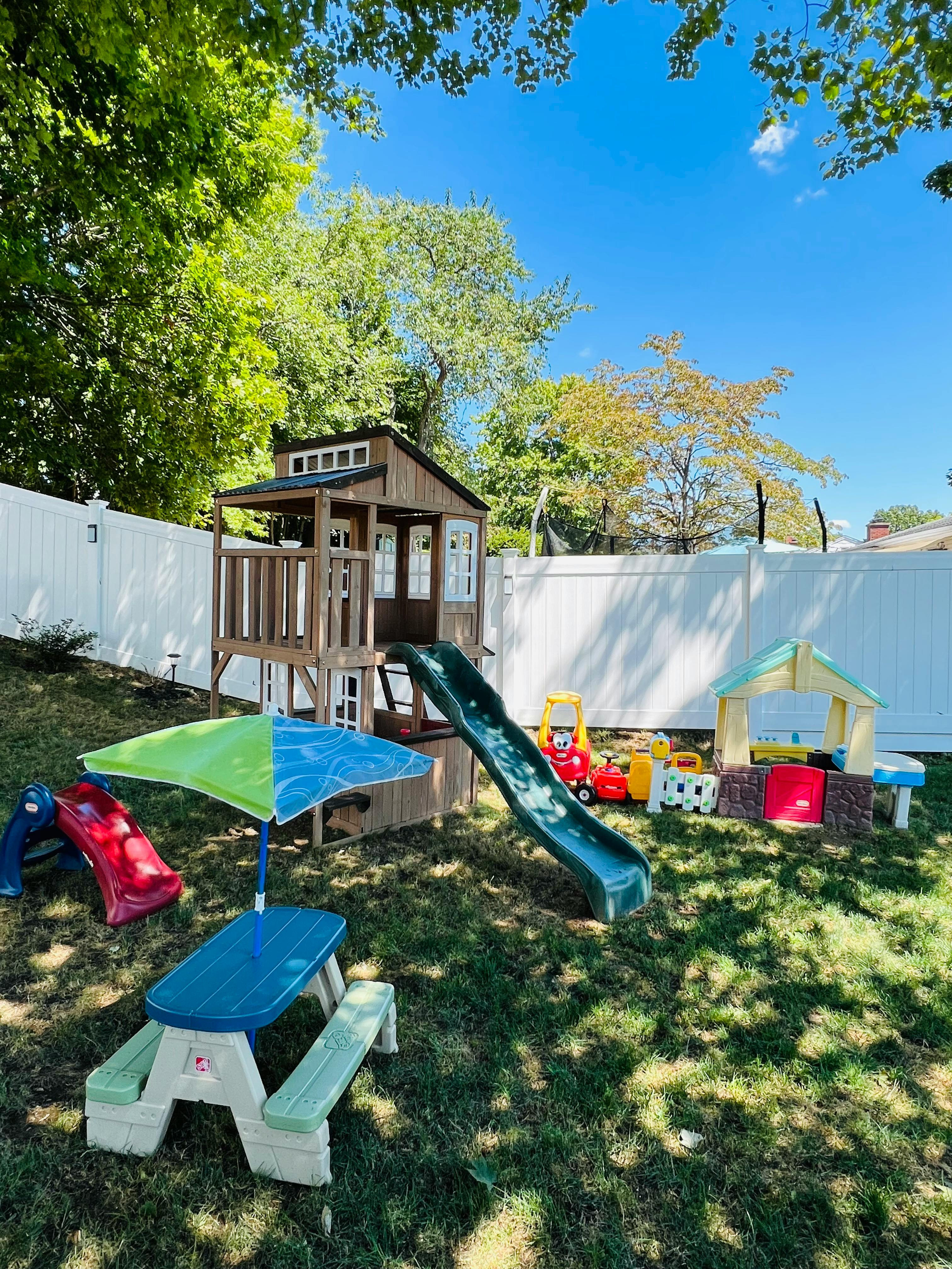 Outdoor playground with a wooden playhouse, slide, and picnic table