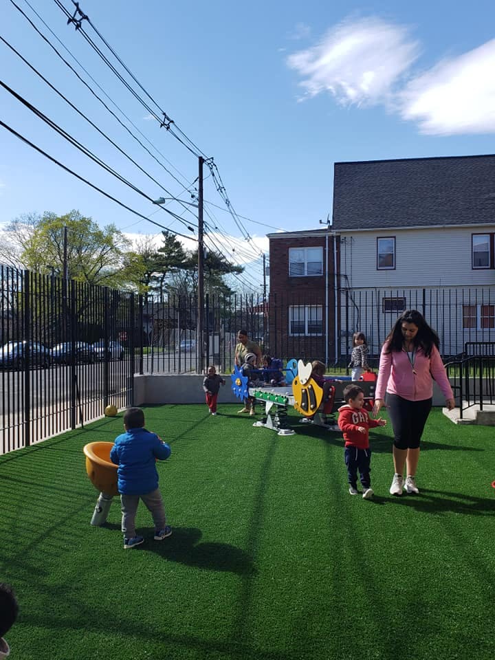 Adults and children on a playground with artificial turf