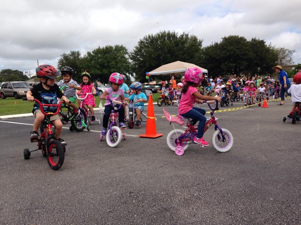 Children on bicycles with helmets on an asphalt surface
