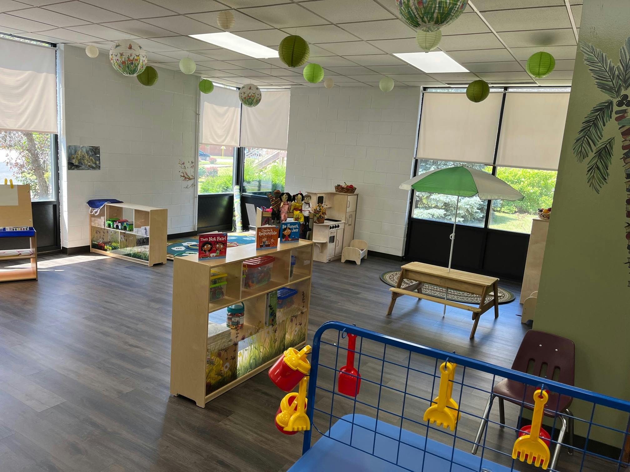 Playroom with shelves of toys, small picnic table with umbrella, and large windows