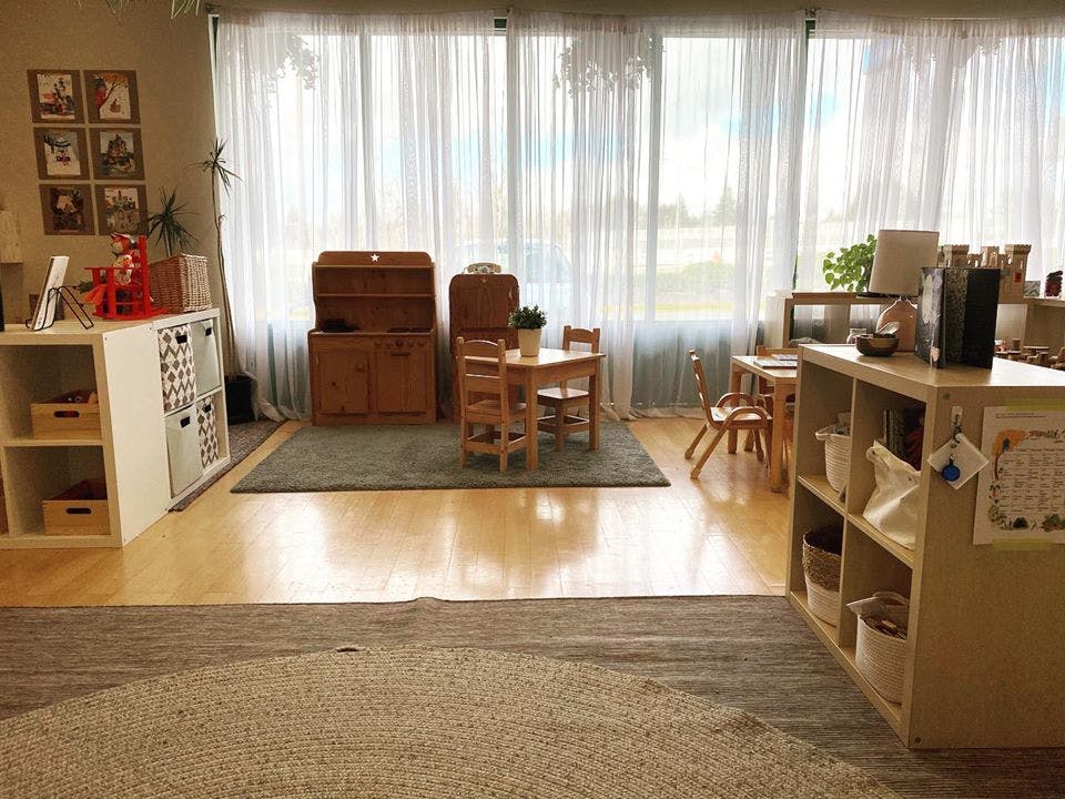 Classroom with small tables and chairs, storage shelves, and large windows