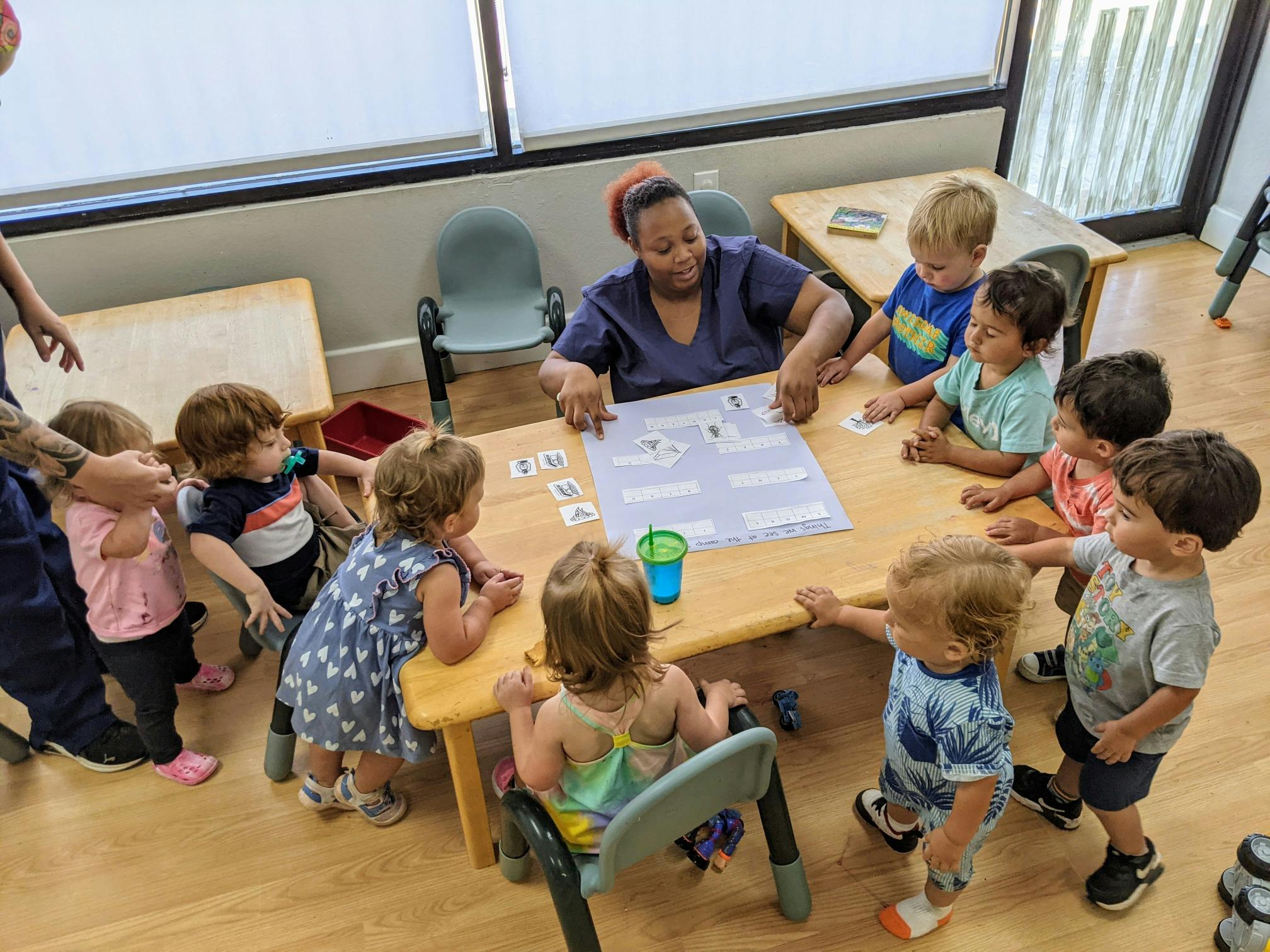 Adult and multiple children gathered around a table in a classroom