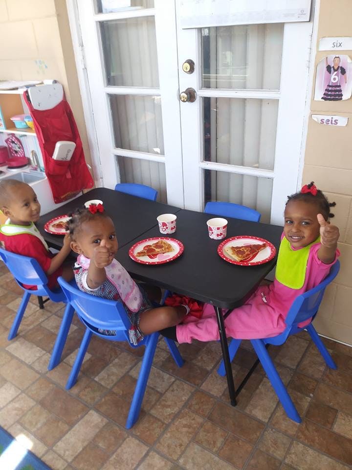 Three children sitting at a table with plates of food