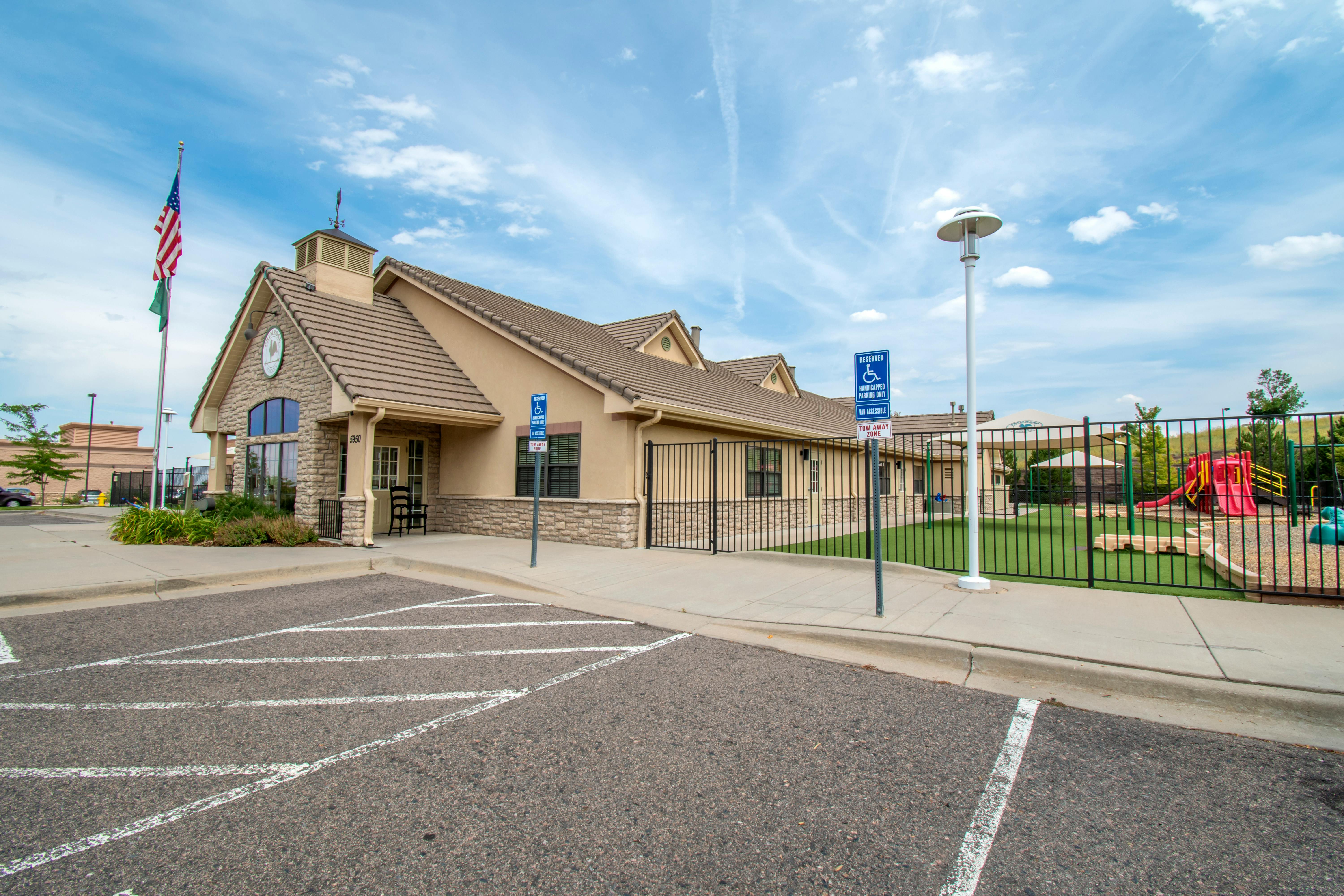 Tan building with a stone facade, a playground, and a handicapped parking sign