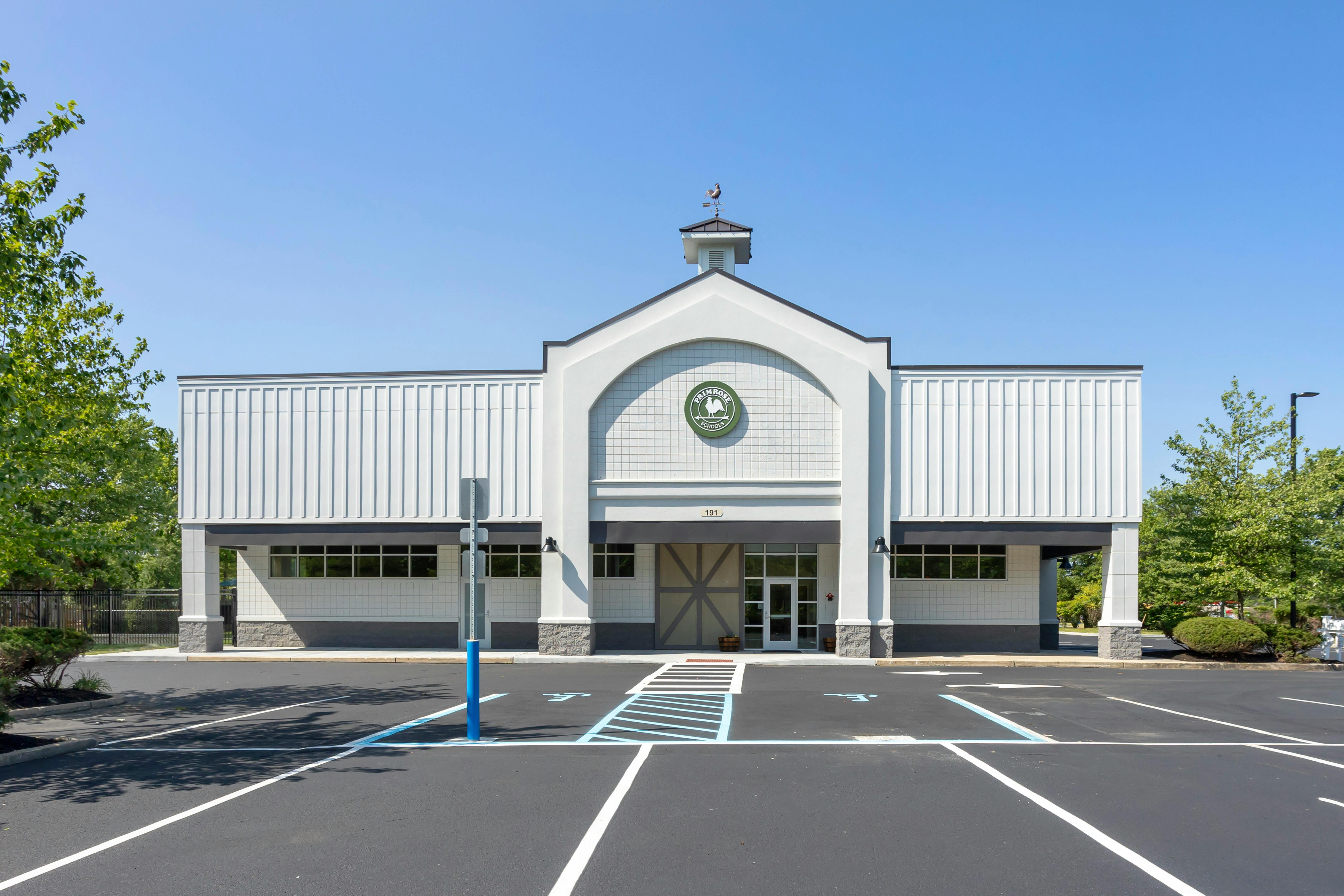 A modern building with a barn-like facade and a green Primrose Schools logo