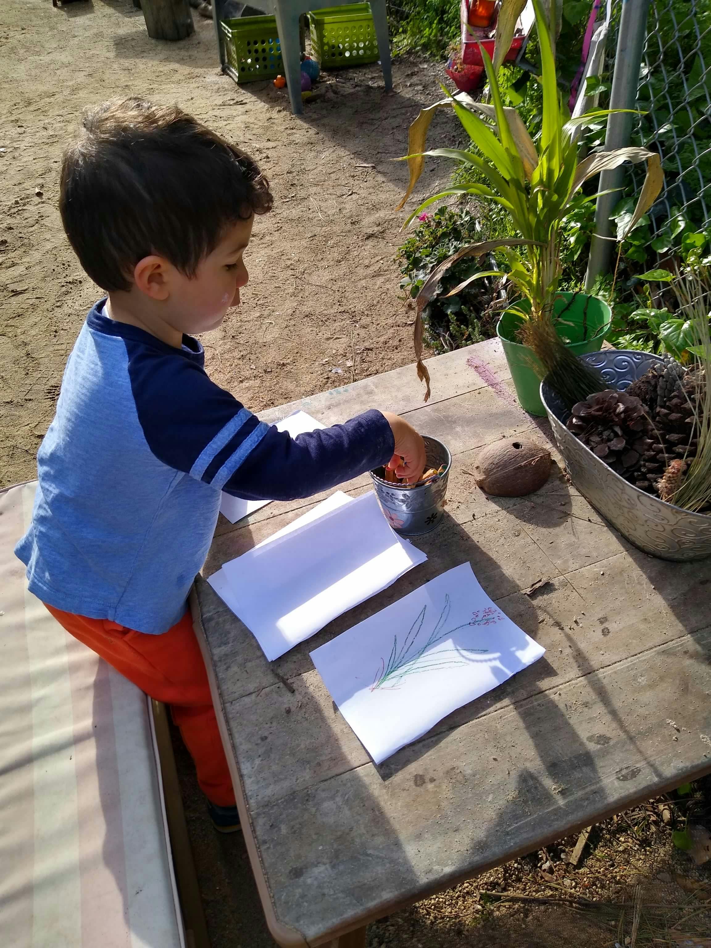 Child sitting at a table with papers and a container