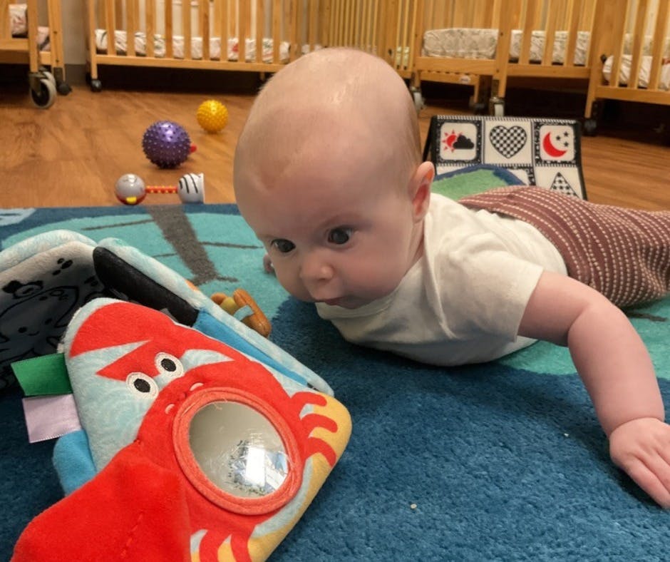 Child on stomach looking at a soft toy with a mirror