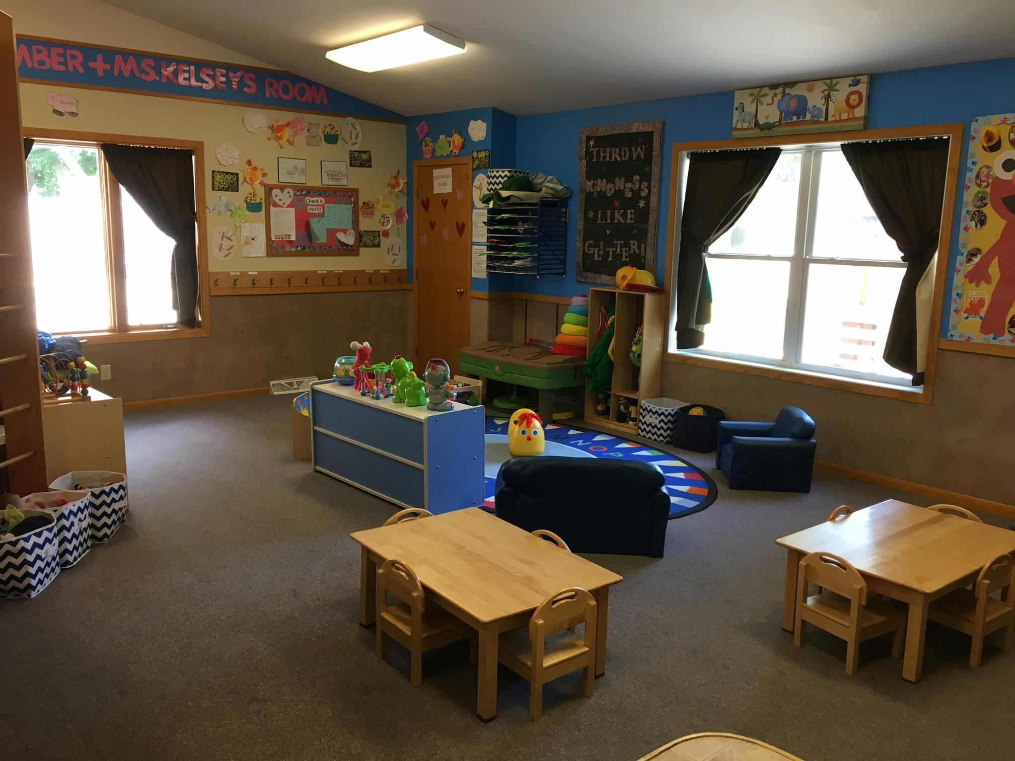 Classroom with small tables and chairs, toys, and windows