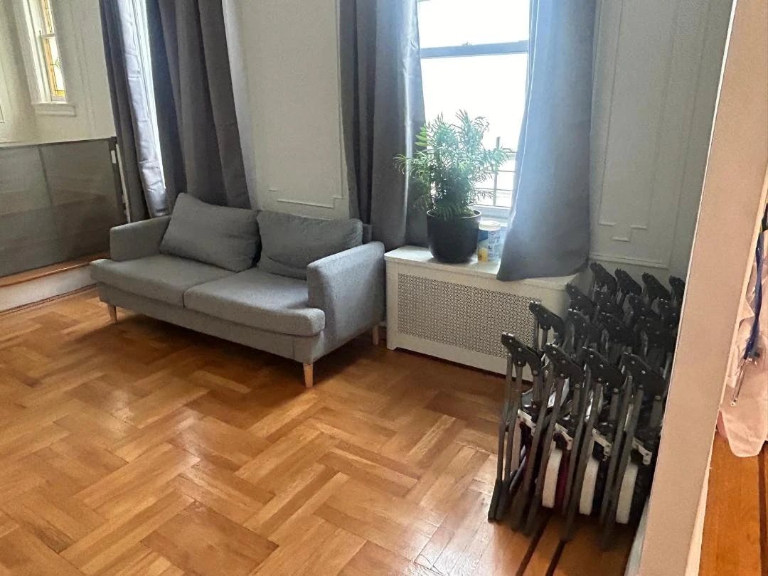 Gray sofa and stacked folding chairs in a room with hardwood floors