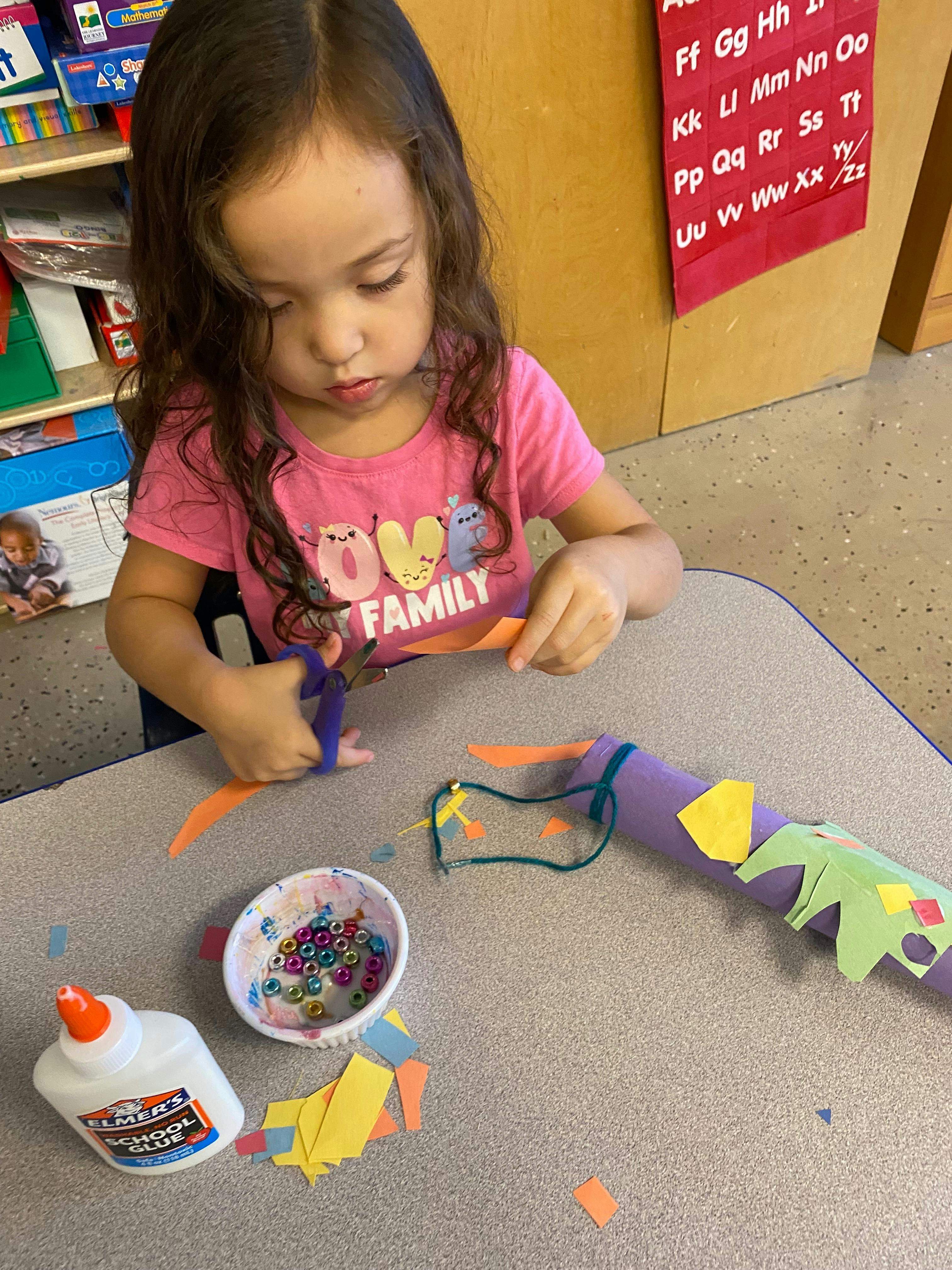 Child cutting orange paper with scissors at a table
